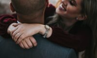man in black suit jacket kissing woman in red shirt