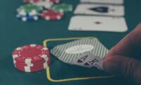 person holding black ace and king spades playing cards on poker table