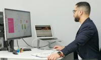 a man sitting at a desk with a laptop and a computer