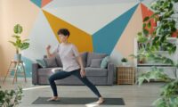 Woman exercising on yoga mat in living room.