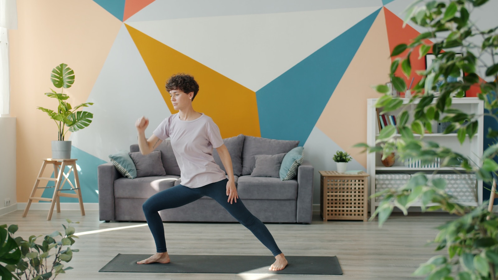 Woman exercising on yoga mat in living room.