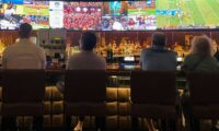 a group of people sitting at a bar watching tv
